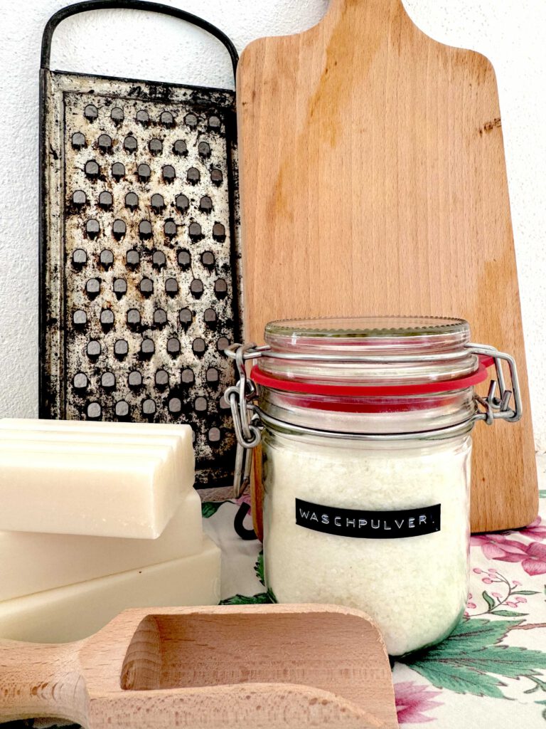 Natural laundry detergent in a glass jar with soap bars and grater